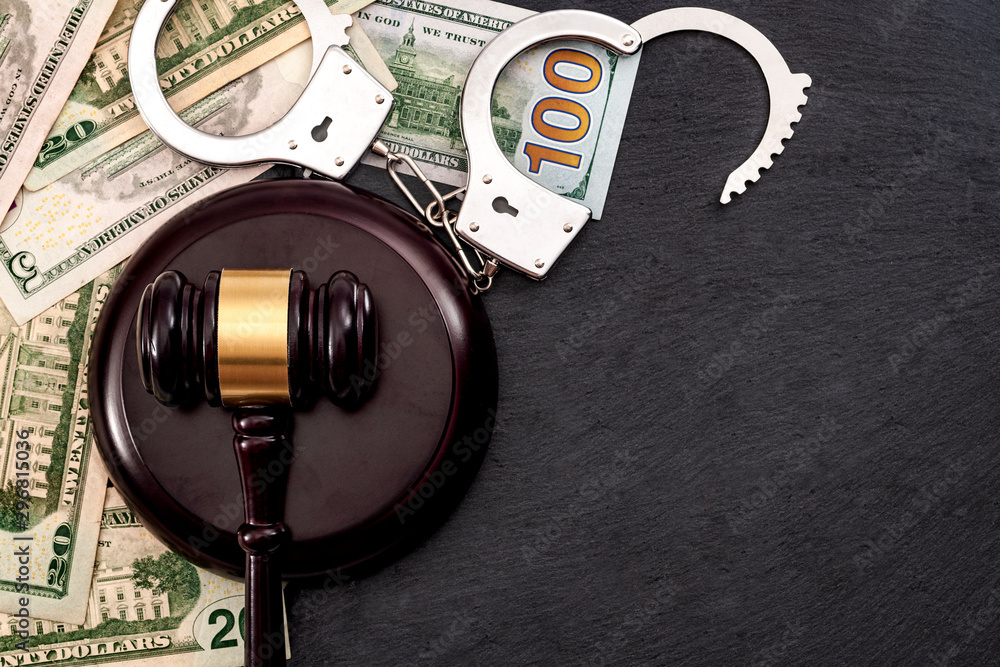 Bail bond system, bailing out of jail and innocent until proven guilty conceptual idea with judge wooden gavel, dollar banknotes and handcuffs with copy space