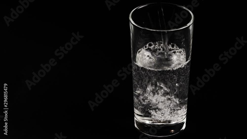 Filing a glass of mineral water on black background