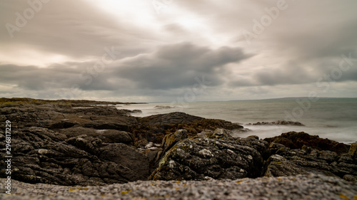 Cloudy sky above rocks, silky smooth water and sharp stones, part of Wild Atlantic Way in Ireland. West Coast