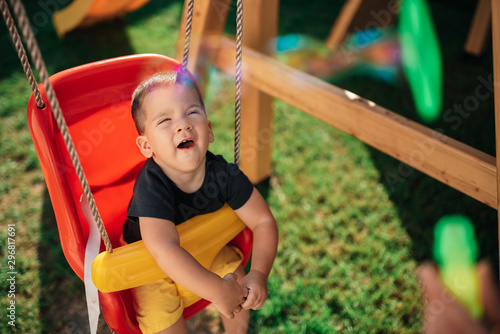 Toddler boy sitting on the swing at backyard and yawning photo