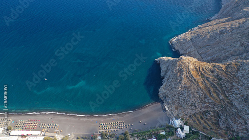 Fototapeta Naklejka Na Ścianę i Meble -  Aerial drone photo of famous seaside village and organised with sun-beds and umbrellas sandy beach of Kamari, Santorini island, Cyclades, Greece