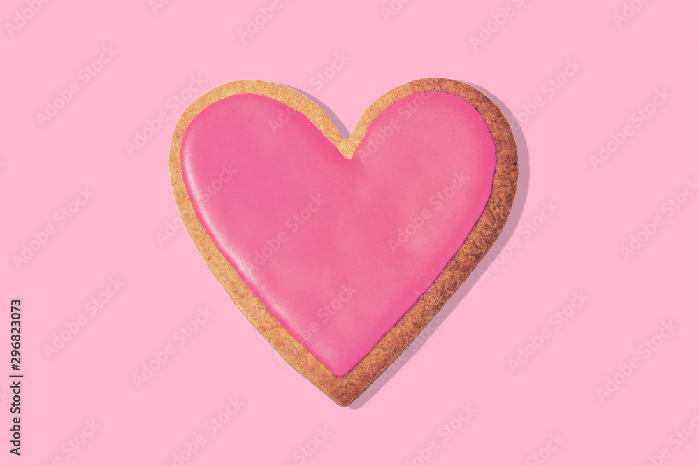 Decorated heart shaped cookie on pink background, top view