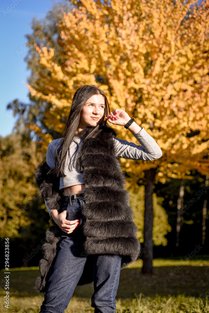 beautiful girl with long hair smiles nicely in the autumn park, fur coat, fur beautiful girl with long hair smiles nicely in the autumn park, fur coat, fur