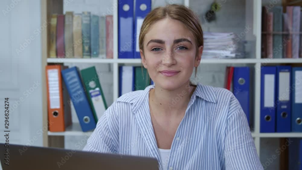 Portrait of pretty smiling young woman enjoying working on notebook computer in comfort office workspace. Satisfied employee. Portrait of pretty smiling young woman enjoying working on notebook computer in comfort office workspace. Satisfied employee.