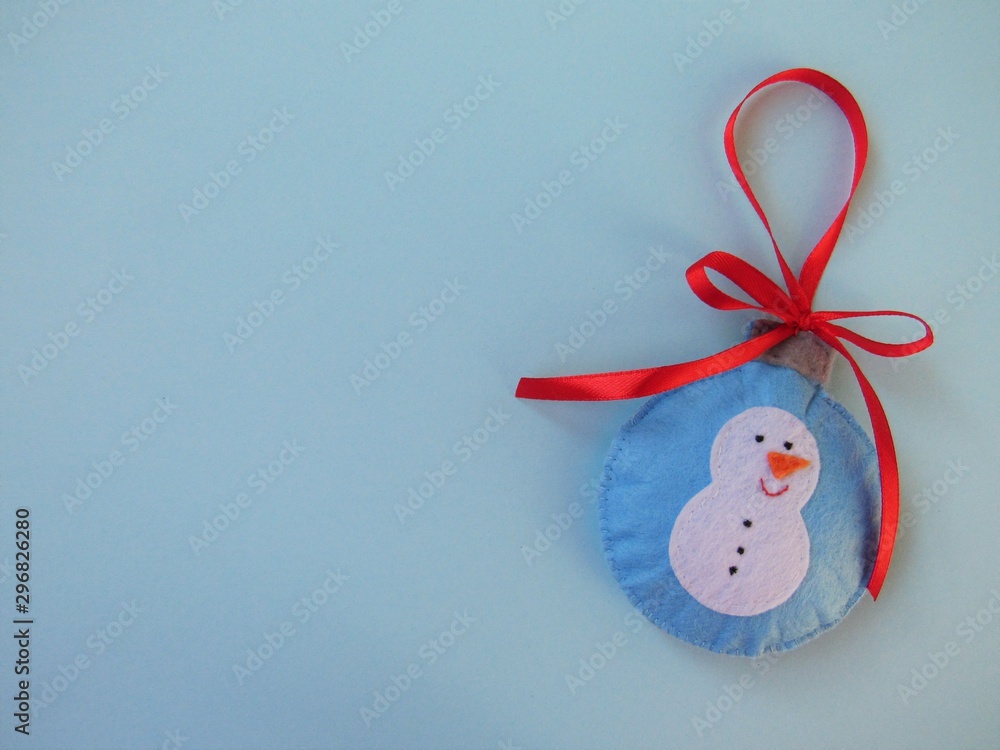 Christmas background. Idea for creativity. Handmade Christmas toy lies on a blue background. A snowman is depicted on a Christmas toy. Space for text.