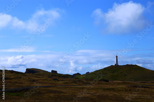 paisaje en islandia con un faro en una montaña y el cielo azul