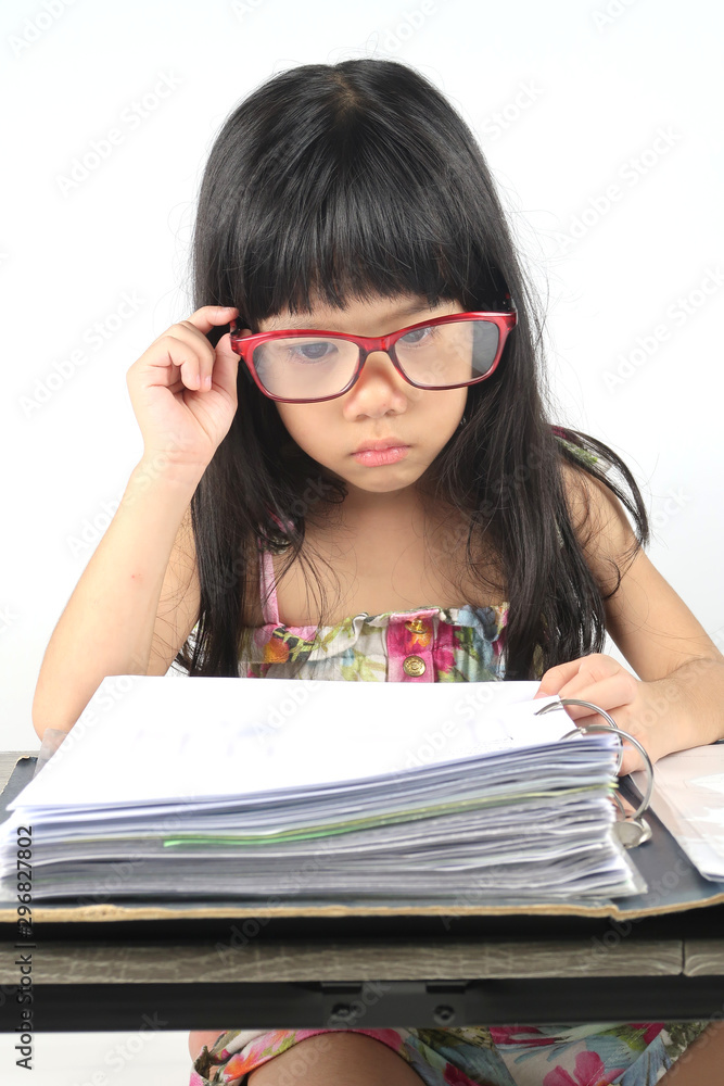 Little girl is playing the roles in concept of hard working people by wears glasses, acting like distressed with a lot of paperwork in front of her. Little girl is playing the roles in concept of hard working people by wears glasses, acting like distressed with a lot of paperwork in front of her.