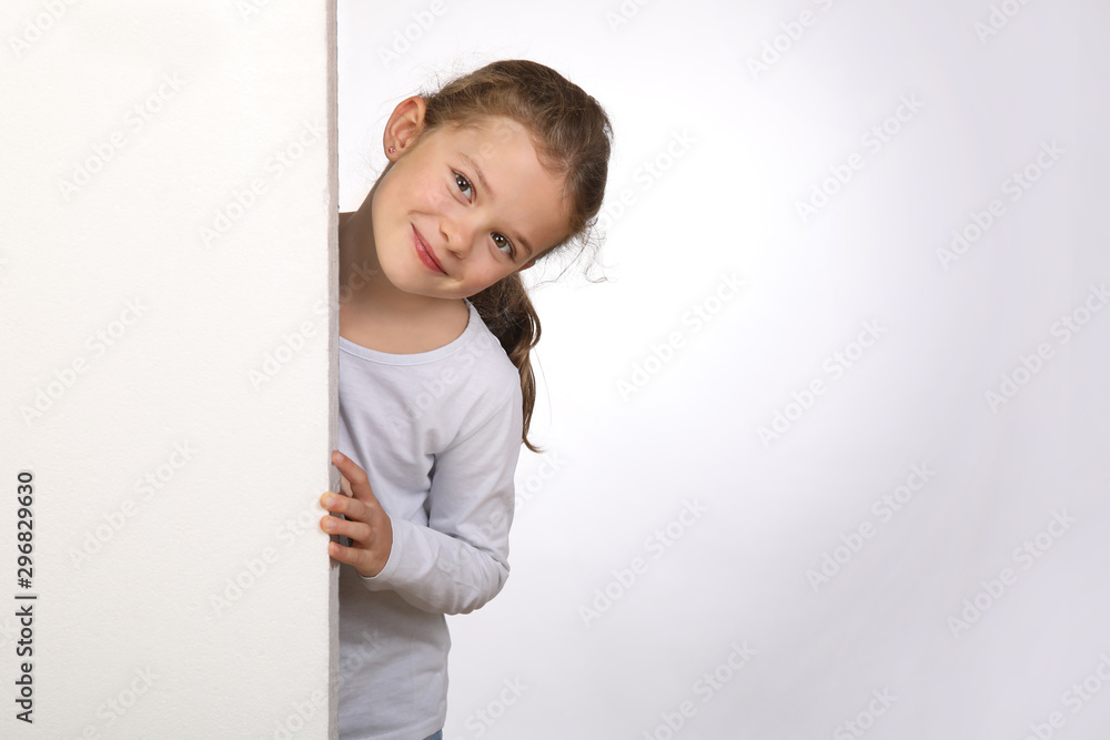 Kleines Mädchen schaut verschmitzt hinter einer Wand hervor Kleines Mädchen schaut verschmitzt hinter einer Wand hervor