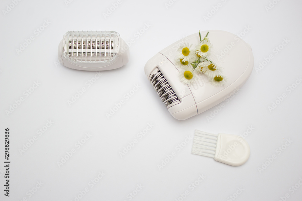 White electric epilator to remove unwanted hair. Beauty and skin care concept. Healing daisy flower White electric epilator to remove unwanted hair. Beauty and skin care concept. Healing daisy flower