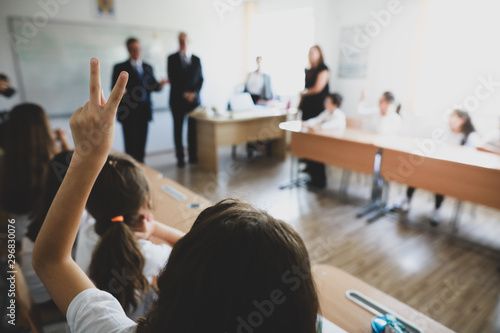 Fototapeta Naklejka Na Ścianę i Meble -  Shallow depth of field image with a pupil raised hand to answer or put a question or to volunteer for a task in the classroom.