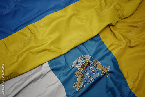 waving colorful flag of canary islands and national flag of ukraine.