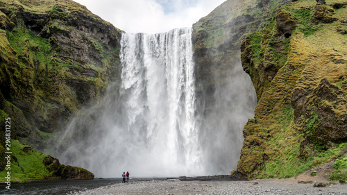 Huge waterfall of Skogafoss with a couple taking photographs  Skogar  south of Iceland