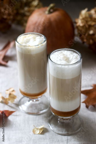 Homemade pumpkin latte in tall glasses and pumpkin on a linen tablecloth. Rustic style.