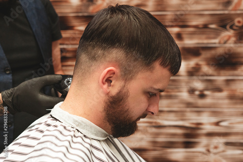 Haircut head in barbershop. Barber cuts the hair on the head of the client. The process of creating hairstyles for men. Barber shop. Selective focus.