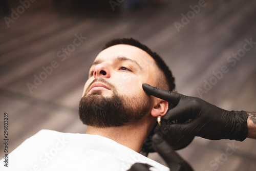 Shaving a beard in a barbershop with a dangerous razor. Barber Shop Beard Care. Drying, cutting, cutting a beard. Selective focus.