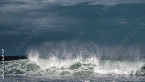 Seascape. Powerful ocean wave on the surface of the ocean. Wave breaks on a shallow bank. Stormy weather  stormy clouds sky background.