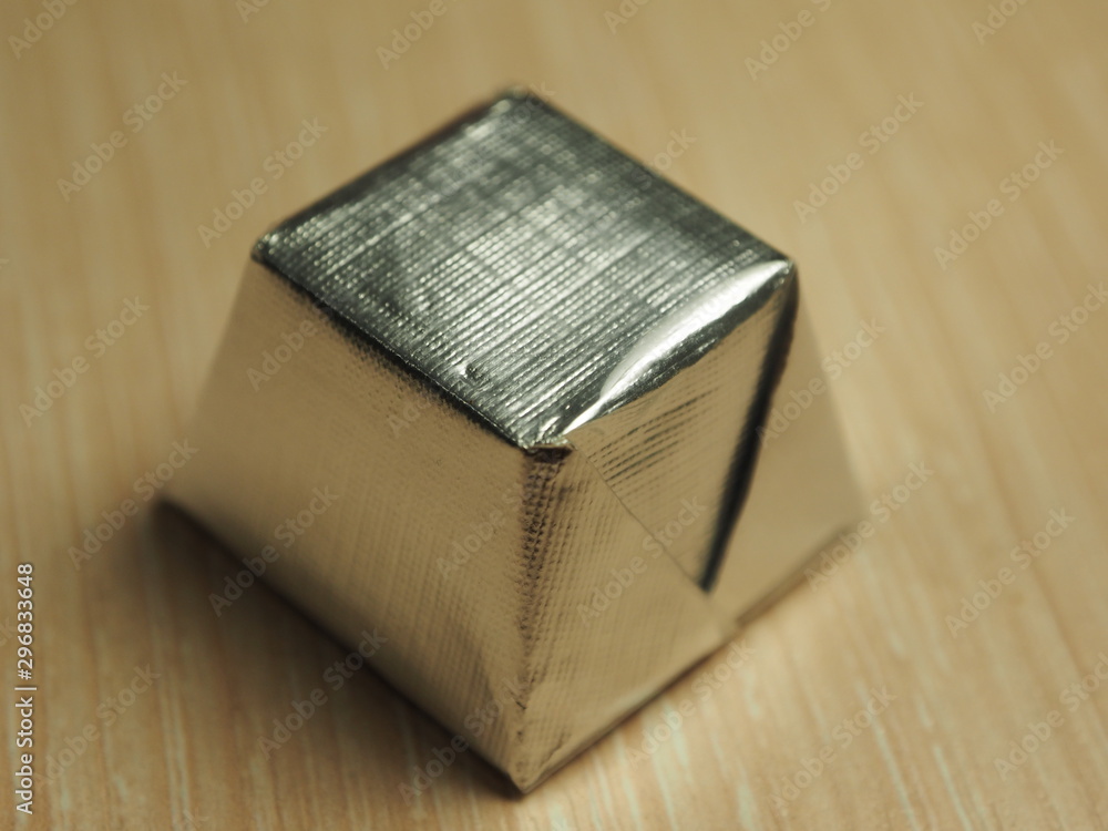 Photo of sweets in a silver wrapper on a light wood background Photo of sweets in a silver wrapper on a light wood background