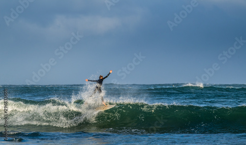 Mossel Bay, South Africa. Surfing the waves. Surfer riding wave with rainbow on storm sky background.