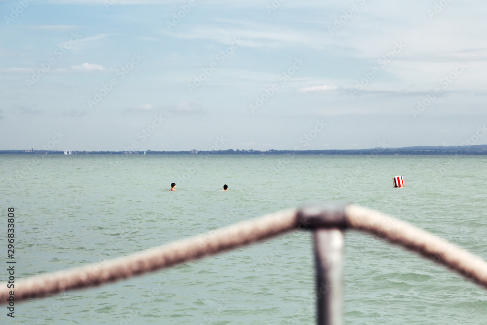 Panoramic view of the Lake Balaton with two swimmwers, a buoy and a  security rope on