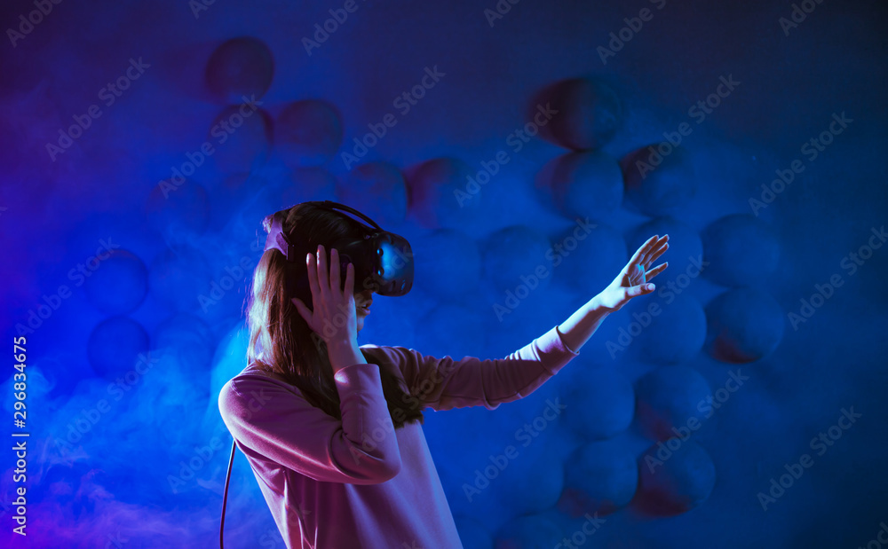 A delighted young woman in virtual reality glasses, against the futuristic background get experience in virtual space. A delighted young woman in virtual reality glasses, against the futuristic background get experience in virtual space.