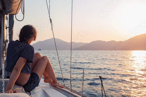 attractive young woman in a striped t-shirt enjoys the sunset on the deck of a sailing yacht. Girl yachtsman © Alexander