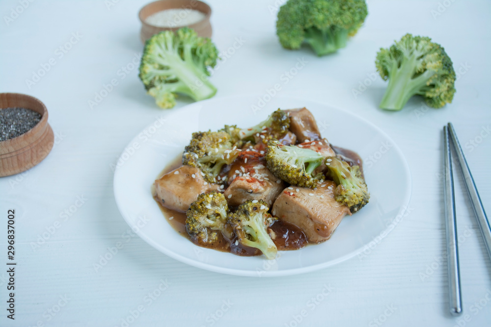 Salad with broccoli and chicken. Hot salad in the sauce served in a white plate. Asian style dish. Light background. Salad with broccoli and chicken. Hot salad in the sauce served in a white plate. Asian style dish. Light background.