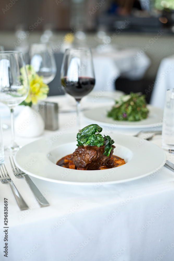 clean white table setting with meal and wine at elegant restaurant clean white table setting with meal and wine at elegant restaurant