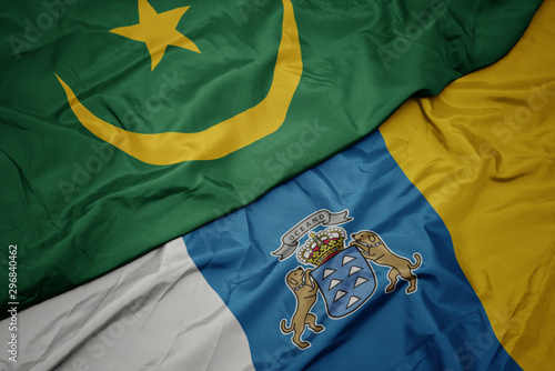 waving colorful flag of canary islands and national flag of mauritania.