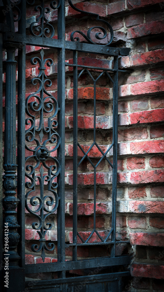 Forged gates black metal fence with red brick wall