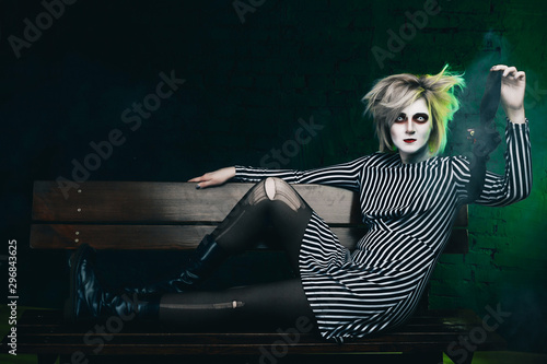 Wallpaper Mural a girl in a terrible striped Halloween costume holds a bat toy in her hand. Halloween makeup. Torontodigital.ca