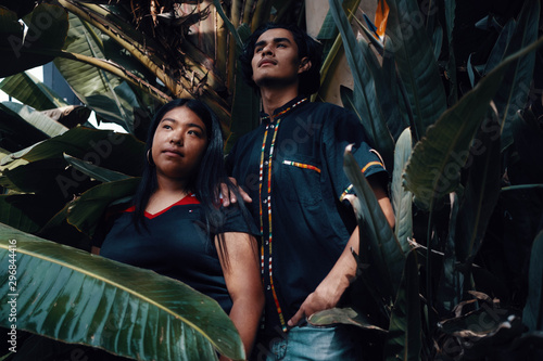 Portrait of teen boy and girl surrounded by tropical plants photo