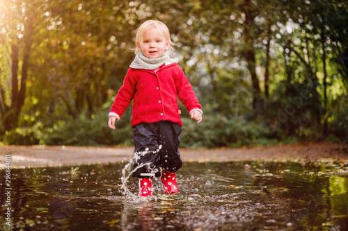 kleinkind spielt in Regenpfütze Matschepfütze im Herbst Spass im Wasser im wunderschönen Herbst