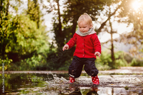 kleinkind spielt in Regenpfütze Plantschen Matschepfütze Spass Freude Sonnenschein im Herbst
