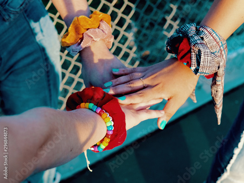 Three hands with bracelets overlapping photo