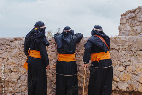 People with traditional attire standing against wall
