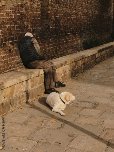 Man sitting against wall with pet beside