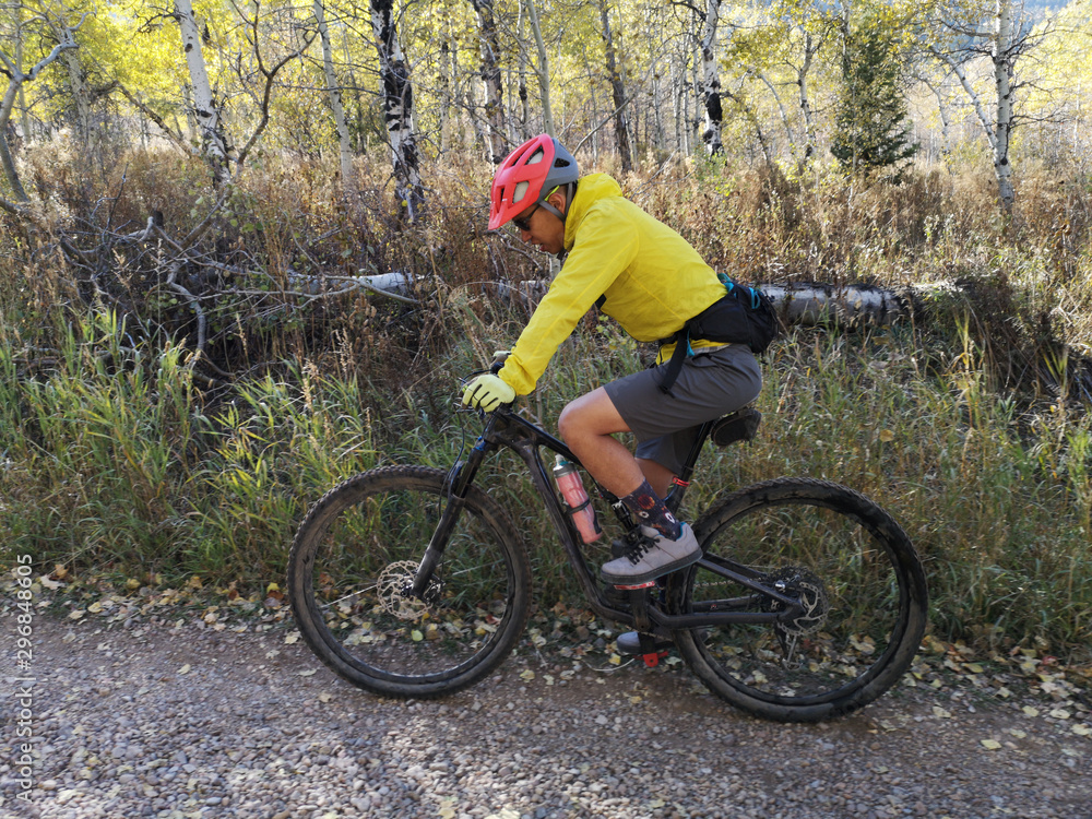 Asian guy with a red helmet and yellow jacket riding a bike around Sardine Peak Trailhead
