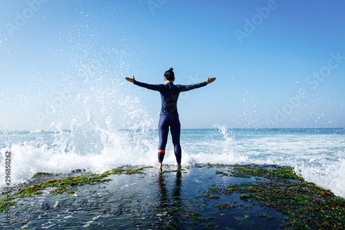 Woman feel free and strong at the seaside cliff edge facing the coming giant sea waves