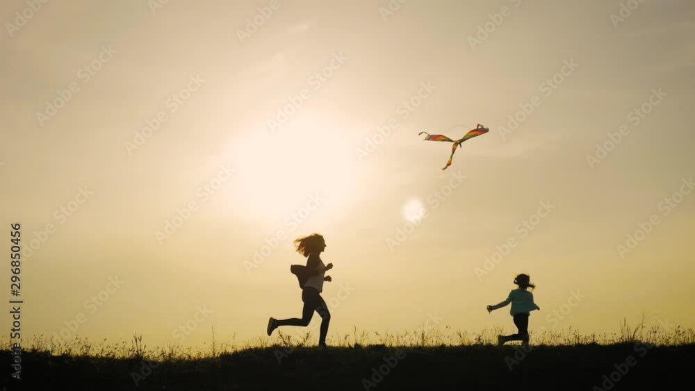 Happy family mother and child daughter launch a kite on meadow at sunset. Funny family time. Concept of friendly family, travel and freedom. Happy family mother and child daughter launch a kite on meadow at sunset. Funny family time. Concept of friendly family, travel and freedom.