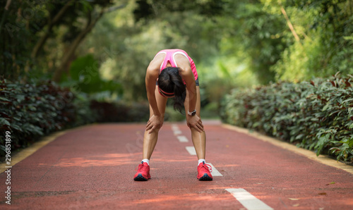 Young fitness woman runner take a break at morning tropical forest trail photo