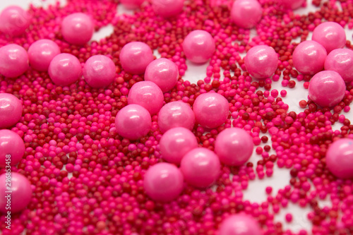 This is a photograph of Pink round sprinkles isolated on a White background © dana_zurki