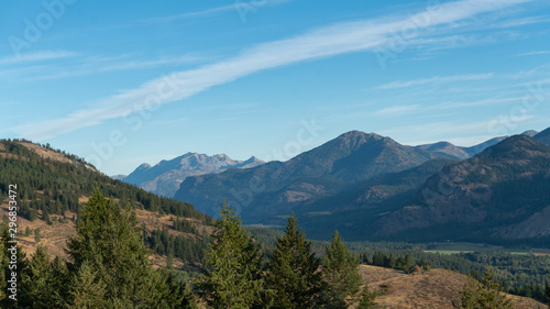 Cabin on a hill dwarfed by the Cascade Mountain Range and Evergreen Pine Trees of Washington State's Okanogan-Wenatchee National Forest Landscape