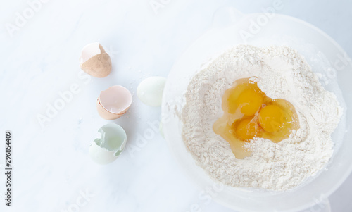 Three Raw Organic Eggs Broken into White Flour to make Dough 