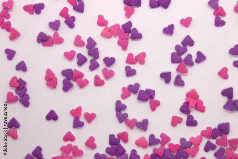 This is a photograph of Pink and Purple heart sprinkles isolated on a White background
