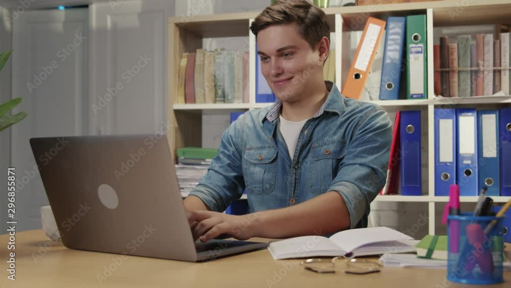 Nice-looking ambitious young man enjoying working in modern office keyboarding on laptop computer. Successful young entrepreneur. Nice-looking ambitious young man enjoying working in modern office keyboarding on laptop computer. Successful young entrepreneur.