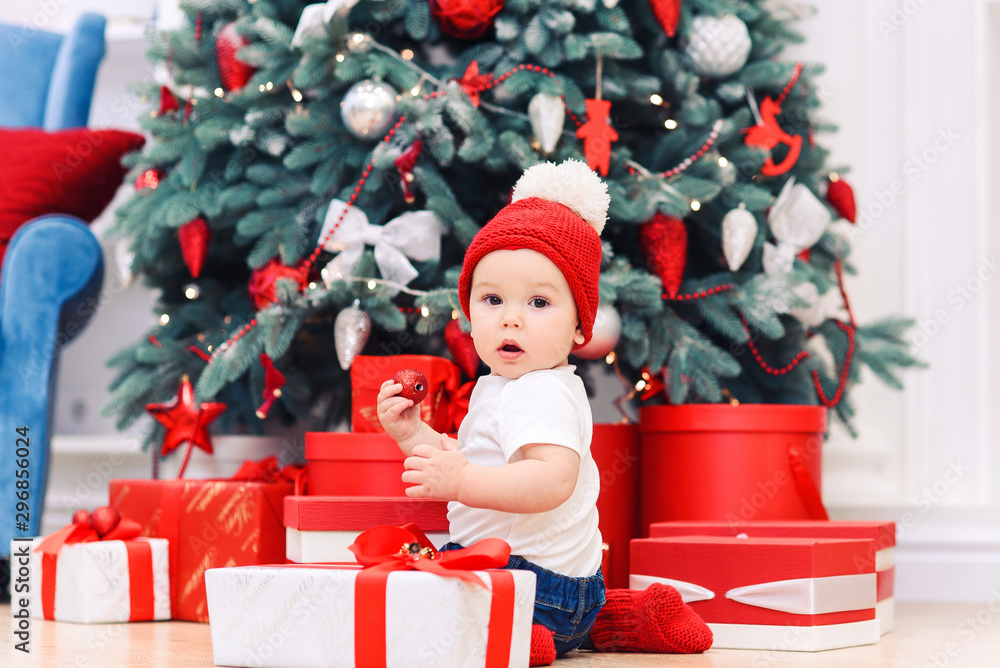 Toddler boy weared in festive clothes playing with christmas gift box. Concept of Christmas and New Year holidays.
