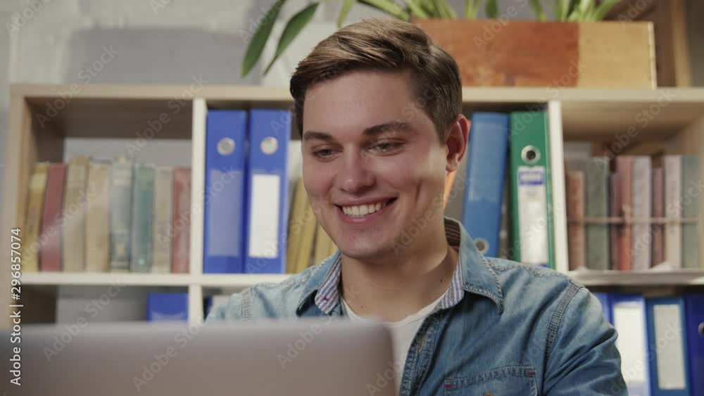 Portrait of happy young man working by computer monitor laughing reading fun content in social network staying in the office.