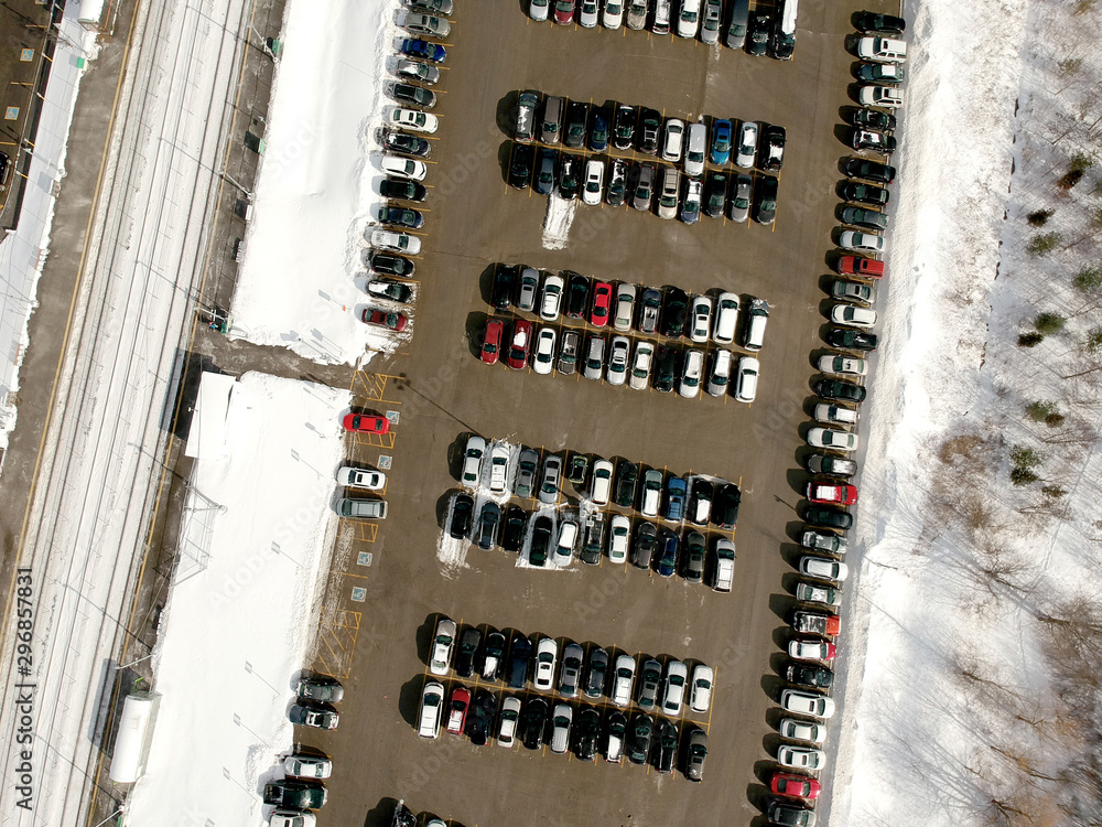 Parking lot filled with cars near commuter train transit at winter. Aerial view. The parking is jammed with cars in winter time. Citizens leaving there cars to travel on train to the city.