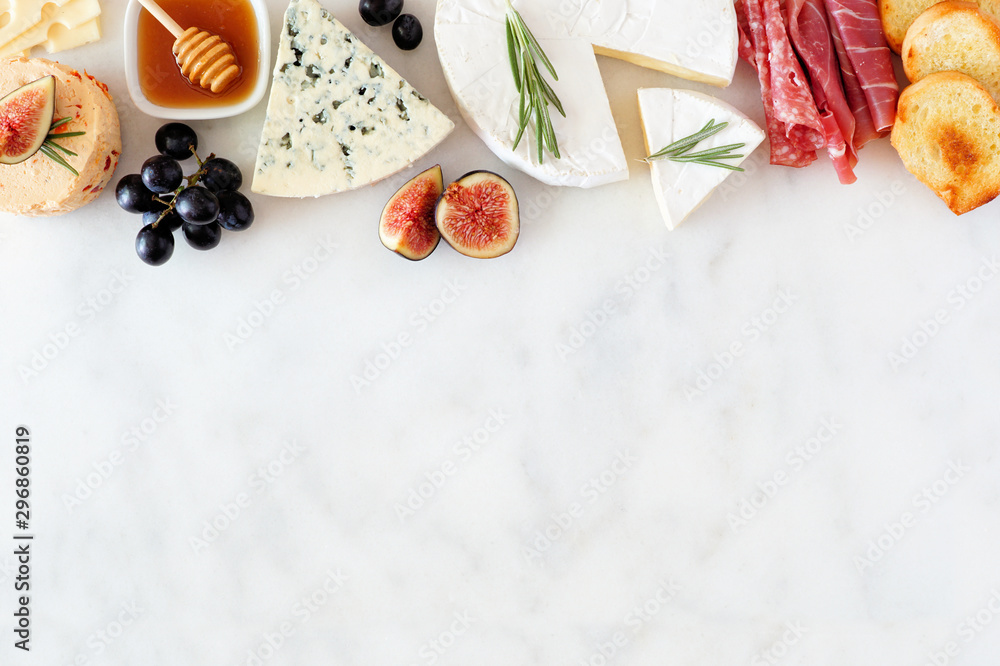 Assorted cheeses and meat appetizers. Top border, overhead view on a white marble background with copy space. - obrazy, fototapety, plakaty 