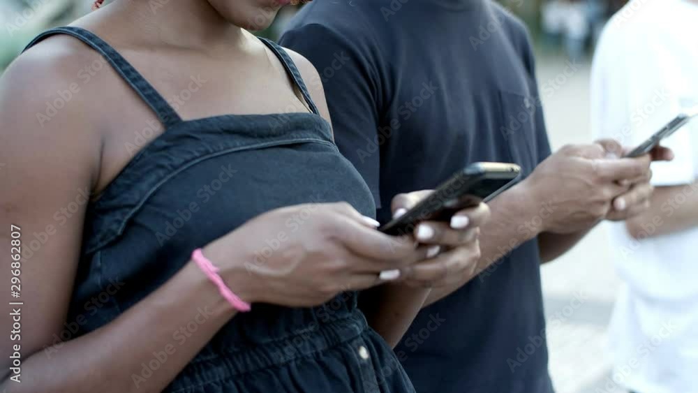 Smiling young woman typing on smartphone. Cheerful African American lady texting with smartphone. Communication and technology concept Smiling young woman typing on smartphone. Cheerful African American lady texting with smartphone. Communication and technology concept